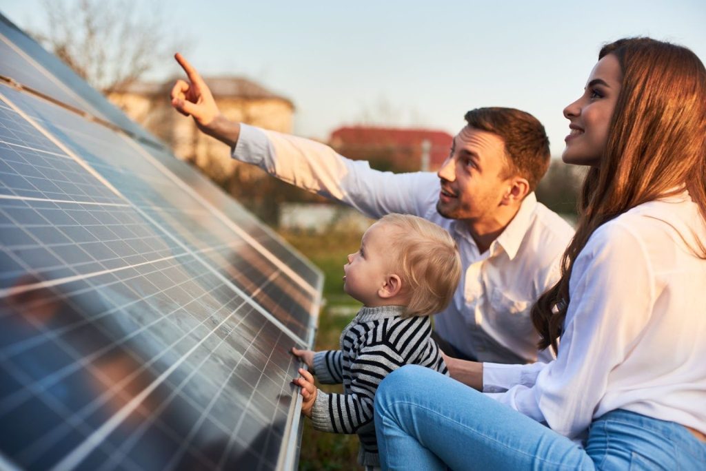 Smiling family looking at new solar panels installed on roof of home