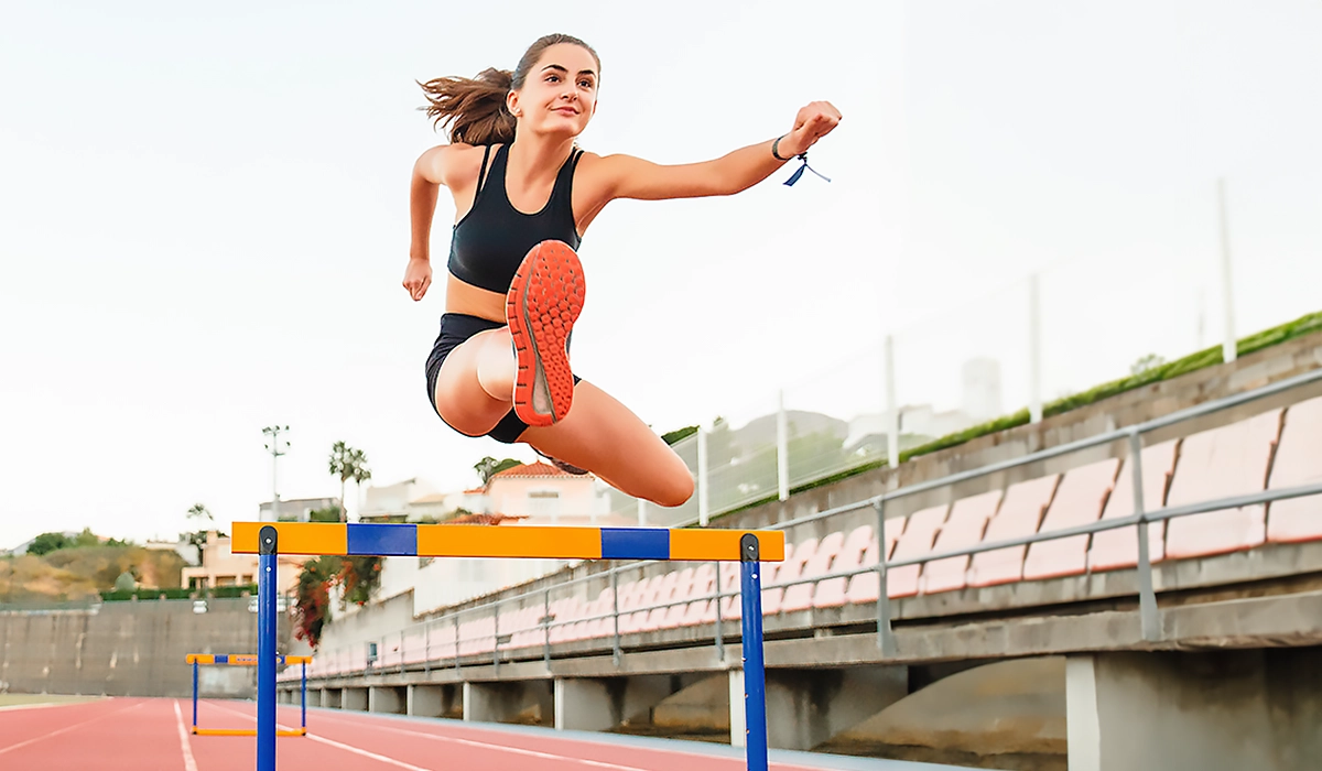 Woman sprinter jumping over hurdles